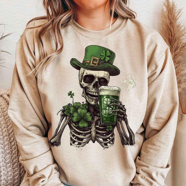 Peut inclure: Sweat-shirt beige avec un squelette portant un chapeau de leprechaun vert et tenant une bi&egrave;re verte. Le squelette est orn&eacute; de tr&egrave;fles. Le verre &agrave; bi&egrave;re a un motif de tr&egrave;fle. Th&egrave;me festif de la Saint-Patrick.
