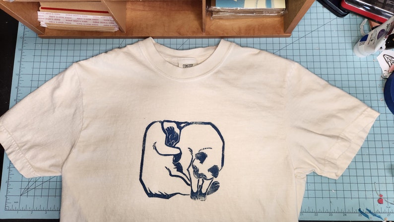May include: White t-shirt with a blue print of two cats curled up together.