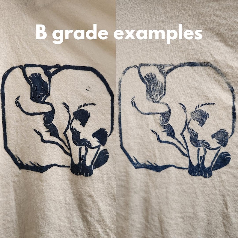 May include: Two examples of a dark blue print of a cat curled up on a light beige t-shirt. The text "B grade examples" is printed above the images.