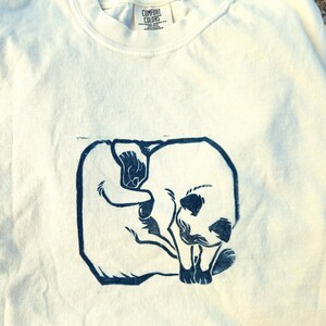 May include: A white t-shirt with a blue screen printed image of two cats cuddling. The t-shirt has a tag that says "Comfort Colors".