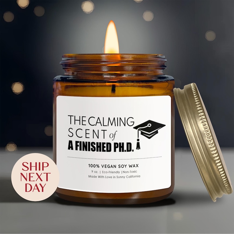 a brown glass jar with a lit candle inside, set against a dark background with a blurred bokeh effect.