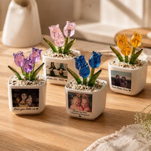 May include: Four square white ceramic planters containing glass tulip flowers in pink, purple, blue, and yellow. Each planter features a custom photograph and text: Love you little sis, Sister Est. 1995, Always my sister, and Best Sister Ever.