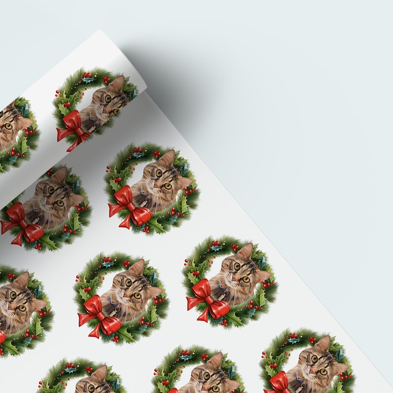 May include: White wrapping paper featuring a repeating pattern of tabby cats inside Christmas wreaths. Each wreath has green foliage, red berries, and a red bow. The cats have brown and tan fur.