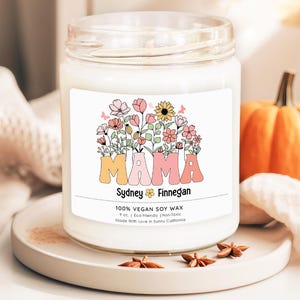 a jar of mama soy candle sitting on a table next to a pumpkin