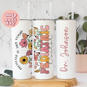 May include: Three white stainless steel tumblers with pink, yellow, and orange floral designs. The tumblers have different text on them: "Protector of Tiny Humans", "Pediatric", and "Dr. Johnson".
