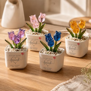 Pode incluir: Quatro vasos quadrados de cerâmica branca contendo flores de tulipa de vidro em roxo, rosa, azul e amarelo. Cada vaso apresenta o texto 'TO A VERY SPECIAL friend' com um balão de coração e 'HAPPY BIRTHDAY' seguido de um nome.