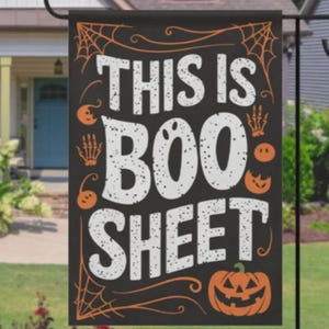 Puede incluir: Una bandera de jardín rectangular negra con el texto blanco THIS IS BOO SHEET en una fuente desgastada. El diseño incluye dibujos lineales naranjas de telarañas en las esquinas, manos de esqueleto y pequeñas calabazas.