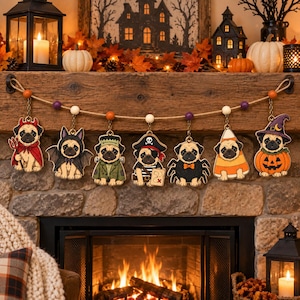 Könnte beinhalten: Eine Halloween-Girlande mit sieben hölzernen Mops-Anhängern in Kostümen, darunter ein Teufel, eine Fledermaus, Frankenstein, ein Pirat, eine Spinne, ein Zuckermais und eine Hexe im Kürbis, aufgereiht an einem Juteseil mit orangefarbenen Perlen.