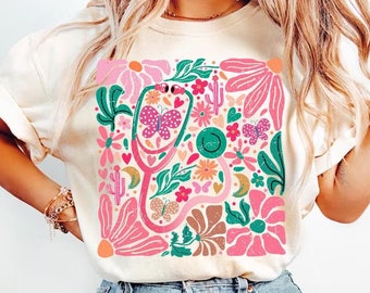 May include: A white t-shirt with a colorful floral design featuring a stethoscope with butterflies and hearts.