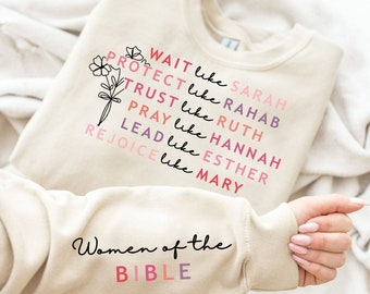 May include: A cream-colored sweatshirt with the words "Wait like Sarah, Protect like Rahab, Trust like Ruth, Pray like Hannah, Lead like Esther, Rejoice like Mary" in pink and purple. The sleeve reads "Women of the Bible."