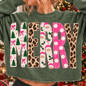 May include: A dark green long-sleeve sweatshirt featuring the word MERRY in large letters. The M has green trees and pink bows, the E has a leopard print, the R has Santa faces and holly, the R has pink polka dots, and the Y has leopard print.