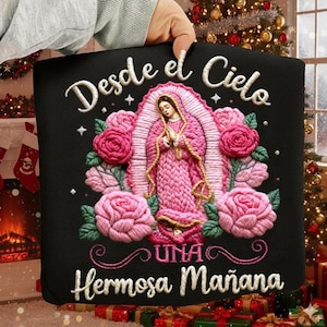 May include: Black decorative pillow with embroidered image of the Virgin Mary in a pink robe, surrounded by pink roses. The text "Desde el Cielo" and "Una Hermosa Mañana" are embroidered in white.