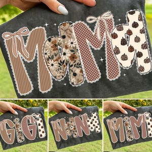Puede incluir: Camisetas de color gris oscuro con las palabras "MOM", "GIGI", "NANA" y "MIMI" en letras decorativas. Las letras presentan varios patrones, incluyendo rayas, lunares, diseños florales y estampado de leopardo. Cada letra tiene un lazo y está delineada con un ribete de encaje blanco.