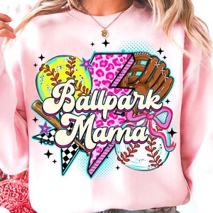 Puede incluir: Sudadera rosa claro con un dise&ntilde;o de b&eacute;isbol. El dise&ntilde;o incluye una pelota, un guante y el texto "Ballpark Mama". El dise&ntilde;o presenta una pelota de s&oacute;ftbol amarilla, un guante marr&oacute;n y un rayo rosa con estampado de leopardo.