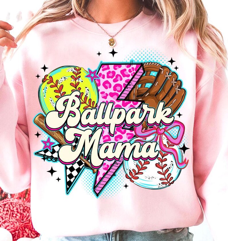Puede incluir: Sudadera rosa claro con un dise&ntilde;o de b&eacute;isbol. El dise&ntilde;o incluye una pelota, un guante y el texto "Ballpark Mama". El dise&ntilde;o presenta una pelota de s&oacute;ftbol amarilla, un guante marr&oacute;n y un rayo rosa con estampado de leopardo.