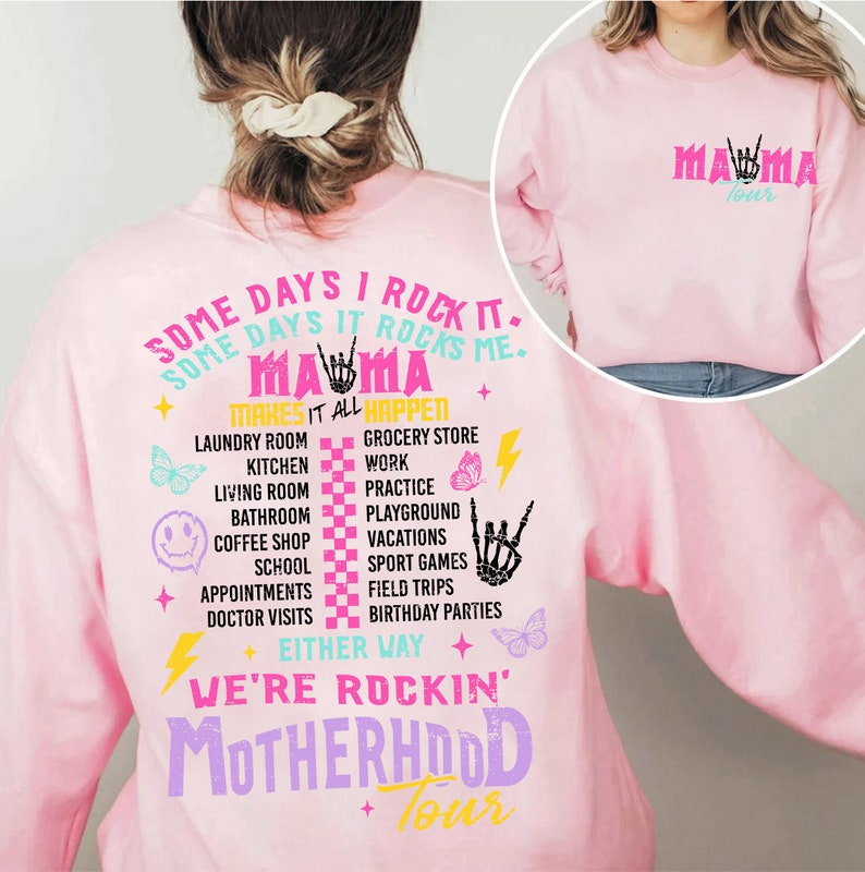 Puede incluir: Sudadera rosa con un dise&ntilde;o gr&aacute;fico que dice "Some days I rock it. Some days it rocks me. Mama makes it all happen." El gr&aacute;fico tambi&eacute;n incluye mariposas, rayos y un patr&oacute;n a cuadros. El texto "We're rockin' Motherhood Tour" tambi&eacute;n est&aacute; incluido en el dise&ntilde;o.