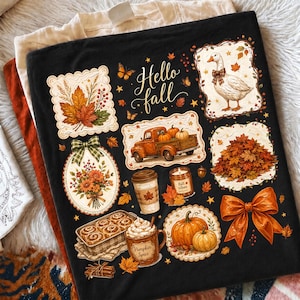 K&ouml;nnte beinhalten: Ein schwarzes T-Shirt mit dem Text Hello fall und verschiedenen herbstlichen Illustrationen, darunter eine Gans mit Schleife, ein Lastwagen mit K&uuml;rbissen, ein Blumenstrau&szlig;, eine Kaffeetasse, eine Kerze, Zimtschnecken und eine gro&szlig;e orangefarbene Schleife.