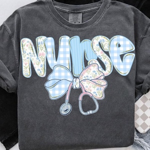 May include: A dark gray t-shirt with the word "NURSE" in blue and pink gingham and floral print. A blue and white gingham bow with a pink floral accent is tied around a stethoscope.