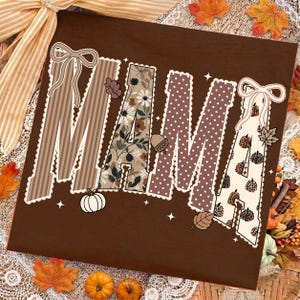 Peut inclure: Un t-shirt marron fonc&eacute; avec le mot MAMA &eacute;crit en grandes lettres majuscules. Chaque lettre pr&eacute;sente un motif unique, notamment des rayures marron, des fleurs, des pois marron et des citrouilles &agrave; imprim&eacute; l&eacute;opard, avec des n&oelig;uds.