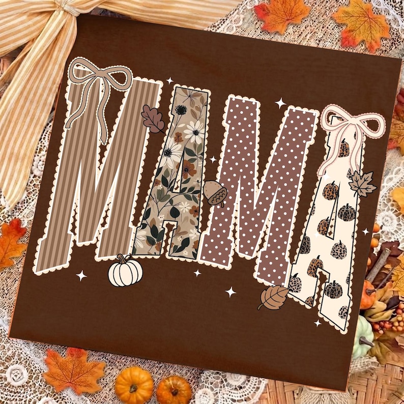 Peut inclure: Un t-shirt marron fonc&eacute; avec le mot MAMA &eacute;crit en grandes lettres majuscules. Chaque lettre pr&eacute;sente un motif unique, notamment des rayures marron, des fleurs, des pois marron et des citrouilles &agrave; imprim&eacute; l&eacute;opard, avec des n&oelig;uds.