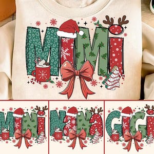 Puede incluir: Una sudadera blanca con un diseño navideño que presenta la palabra "MIMI" en letras verdes y rojas con un lazo rojo, copos de nieve y una taza de chocolate caliente. El diseño se repite con las palabras "NANA" y "GIGI" en la parte inferior.