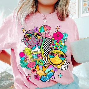 Peut inclure: T-shirt rose avec un motif graphique color&eacute; repr&eacute;sentant un visage souriant avec des lunettes de soleil, des palmiers, une past&egrave;que, un flamant rose, un parasol de plage et le texte "Summer Vibes".