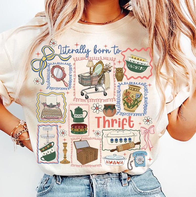 May include: Cream-colored sweatshirt with a colorful graphic design featuring the text "Literally born to Thrift." The design includes illustrations of vintage items like a shopping cart, owl, teapot, and telephone.