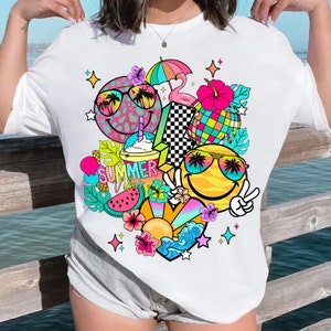 Peut inclure: T-shirt blanc avec un imprim&eacute; graphique color&eacute; repr&eacute;sentant un visage souriant, des lunettes de soleil, une past&egrave;que, une boisson, un flamant rose et le texte "Summer Vibes".