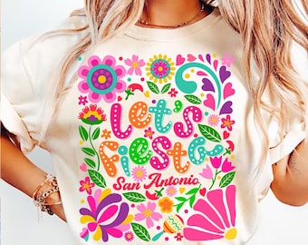 May include: A white t-shirt with a colorful floral design and the text "Let's Fiesta San Antonio".