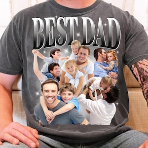 May include: Dark gray t-shirt with the text "BEST DAD" in a silver, 3D-style font. The shirt features a collage of fathers and children. The design includes multiple images of fathers with their children, creating a heartwarming theme.