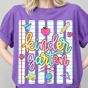 Peut inclure: Un t-shirt violet avec un motif "Kindergarten" color&eacute;. Le motif comprend un avion en papier, une pomme, un crayon, des fleurs, un bus scolaire, un n&oelig;ud, un globe et un triangle. Le t-shirt a un fond de papier de cahier.