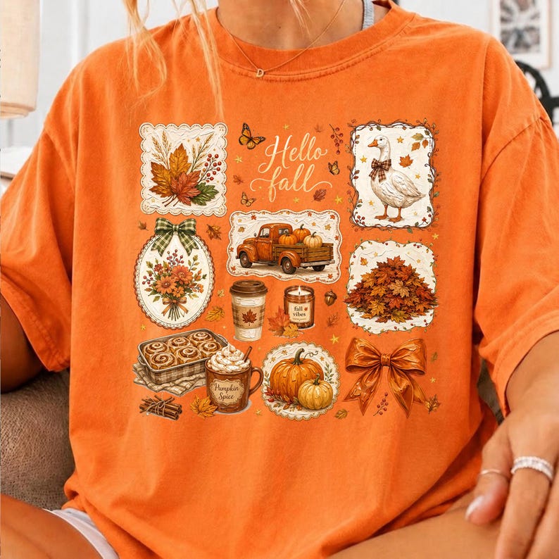 K&ouml;nnte beinhalten: Ein orangefarbenes T-Shirt mit einer Collage aus herbstlichen Illustrationen, darunter eine Gans, ein Lastwagen mit K&uuml;rbissen, ein Kaffeebecher, Zimtschnecken, eine Schleife und Bl&auml;tter. Der Text "Hello fall" ist mittig in Schreibschrift gedruckt.