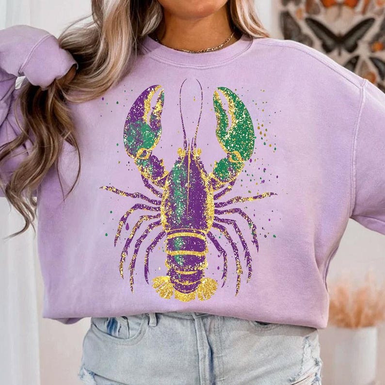 May include: A lavender sweatshirt with a gold, purple, and green glitter lobster design.
