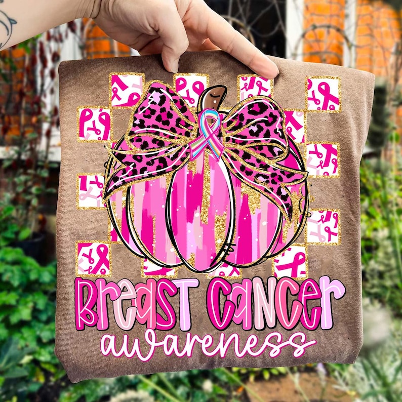 May include: A brown square with a pink pumpkin design, a leopard print bow, and the words "Breast Cancer Awareness" in pink. The pumpkin has gold glitter accents and a pink ribbon. Small pink ribbon squares are in the background.
