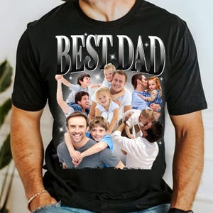 May include: Black t-shirt with a graphic that says "BEST DAD" in silver lettering. The graphic features a collage of photos of fathers and children. The shirt is made of a soft material.