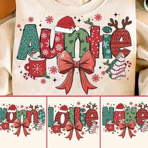 May include: A white sweatshirt with a festive Christmas design featuring the word "Auntie" in red, green, and white with a red bow and a cup of hot cocoa. The design also includes a Christmas tree and reindeer.