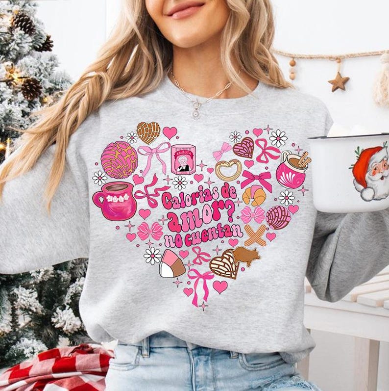 May include: A gray sweatshirt with a pink heart design featuring various Mexican sweets and the text "Calorias de amor? No cuentan".
