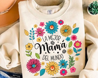 May include: A cream-colored sweatshirt with a floral design and the text "La Mejor Mamá Del Mundo" in black. The flowers are in shades of pink, yellow, blue, and green.