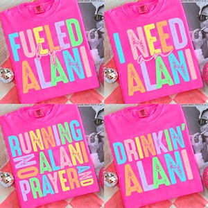 May include: Four hot pink t-shirts with colorful text. The shirts say "Fueled by Alani", "I Need Alani", "Running on Alani and Prayer", and "Drinkin' Alani". Each shirt has a crew neck.