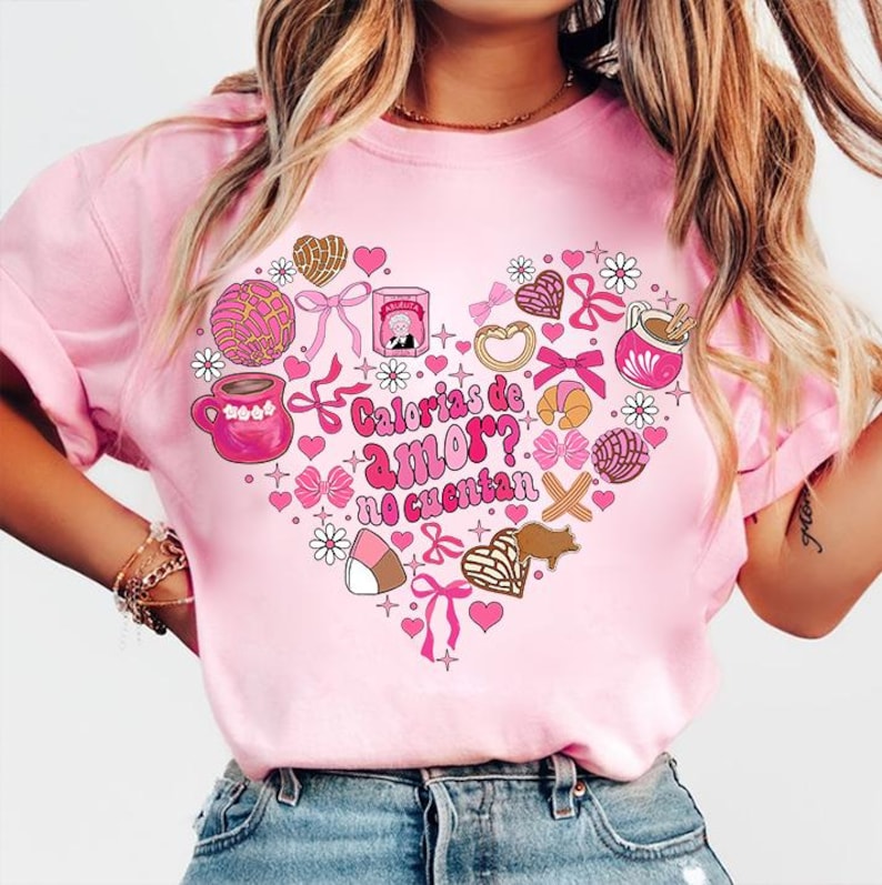 May include: Pink t-shirt with a heart-shaped design featuring various Mexican pastries and the text "Calorias de amor? No cuentan".