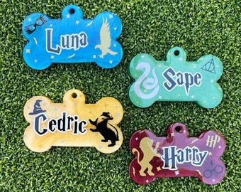 May include: Four colorful bone-shaped dog tags with Harry Potter themed designs. The tags are blue, green, yellow, and red with glitter accents. The names Luna, Snape, Cedric, and Harry are written on the tags.