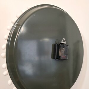 Peut inclure: L'arri&egrave;re d'une horloge ronde vert fonc&eacute; avec une bordure blanche et des points blancs autour du bord. L'horloge a un m&eacute;canisme d'horloge noir avec un crochet argent&eacute;.