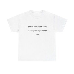 Peut inclure: T-shirt blanc avec l'inscription noire : "I never lead by example, I always let my example Lead". Le t-shirt a un col rond et des manches courtes. Le tissu semble être un mélange de coton doux.