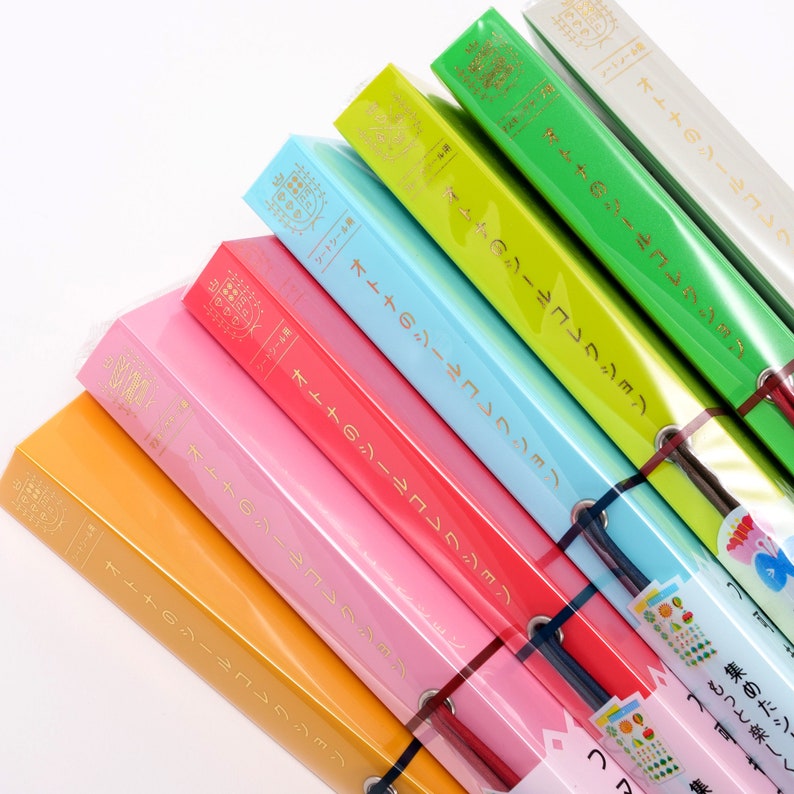 May include: A stack of colorful binders with the text "オトナのシールコレクション" (Adult Sticker Collection) printed on the spines. The binders are arranged in a rainbow pattern, starting with orange and ending with green.
