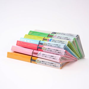 May include: A stack of colorful notebooks with Japanese text on the covers. The notebooks are all different colors, including pink, blue, green, and yellow. The text on the covers says "More fun, more convenient. Organize your stickers and tapes."