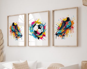 May include: Three framed prints with a colorful watercolor-style design. The prints feature a soccer ball, a soccer cleat, and another soccer cleat. The prints are hung on a white wall above a white daybed with a beige blanket.