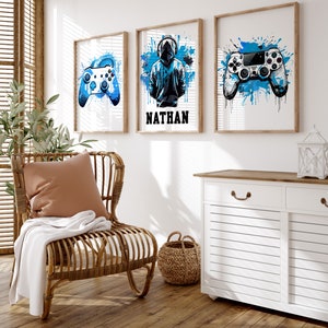 May include: Three framed prints with a blue and white watercolor background. The prints feature a video game controller, a person wearing a hooded sweatshirt, and the name "Nathan".