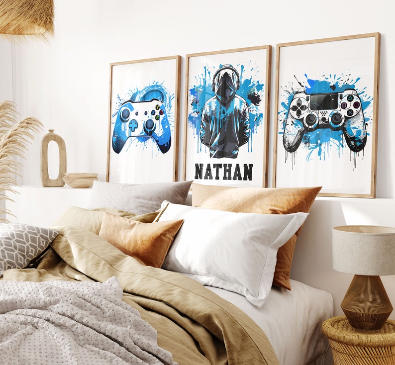 May include: Three framed prints with blue watercolor splashes and gamer-themed illustrations. The prints feature a video game controller, a hooded figure, and the name "NATHAN".