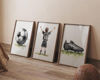 Puede incluir: Tres ilustraciones de acuarela enmarcadas de un jugador de fútbol, un balón de fútbol y una bota de fútbol. El jugador lleva una camiseta negra con el número 10 en la espalda. El balón de fútbol es negro y blanco. La bota es negra y tiene una suela blanca.