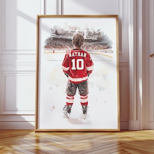 May include: A watercolor painting of a young hockey player wearing a red and white jersey with the name "Nathan" and the number "10" on the back. The player is standing on a snowy ice rink, looking out at a crowd of spectators in the background.